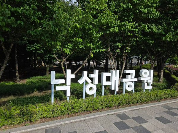낙성대공원 나무들 앞에 세워진 흰색 '낙성대공원' 한글 글자 조형물