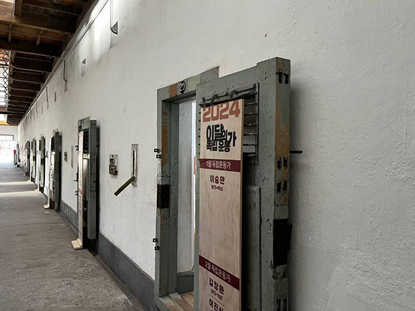 서대문형무소역사관 이달의 독립운동가' 안내판이 붙어 있는 좁고 긴 복도 형태의 형무소 감방 입구들