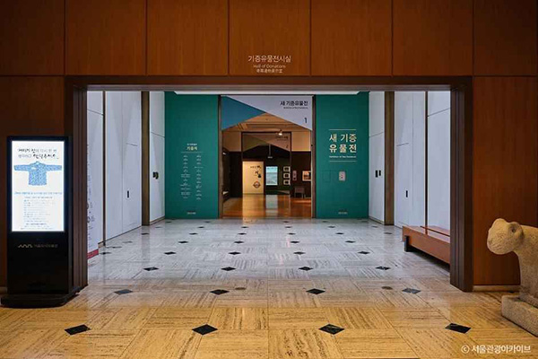 서울역사박물관 새 기증 유물전' 안내 문구가 적힌 민트색 벽면의 기증유물전시실 입구
