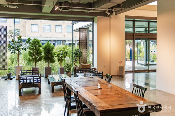 양주 조명박물관 커다란 통유리창을 통해 정원이 보이는 쾌적한 박물관 내부 휴게 공간과 원목 탁자